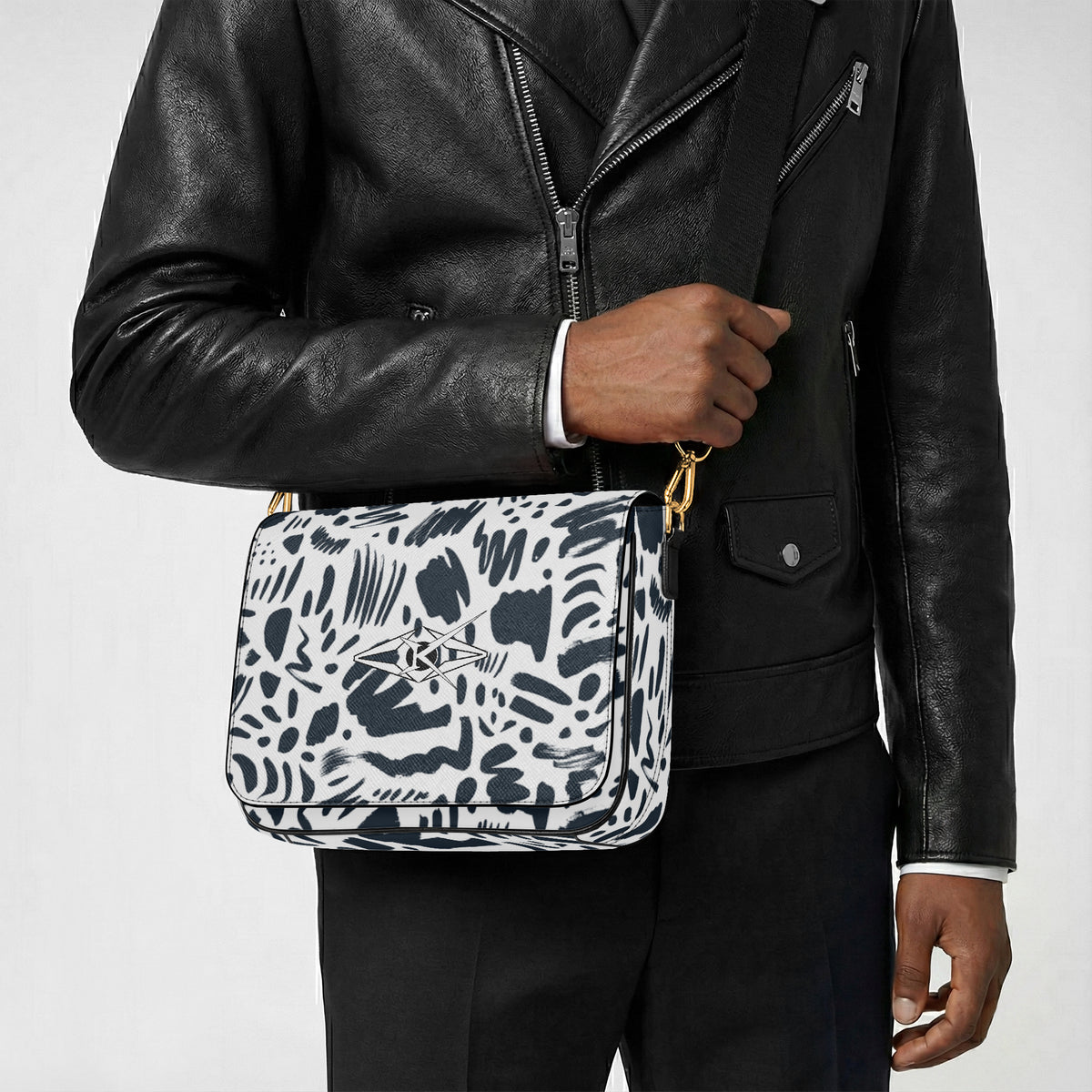 Person holding a patterned bag with a black leather jacket on a light gray background