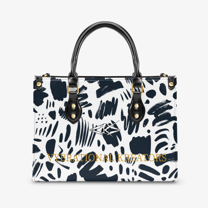 Kreator Luxe tote bag by Vybrational Kreators featuring a black and white abstract pattern structured shape black top handles gold hardware and printed brand logo.