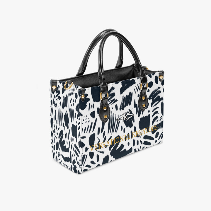 Kreator Luxe tote bag by Vybrational Kreators featuring a black and white abstract pattern structured shape black top handles gold hardware and printed brand logo.