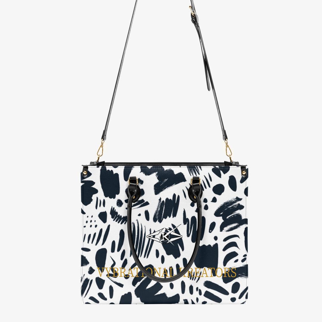 Kreator Luxe tote bag by Vybrational Kreators featuring a black and white abstract pattern structured shape black top handles gold hardware and printed brand logo.