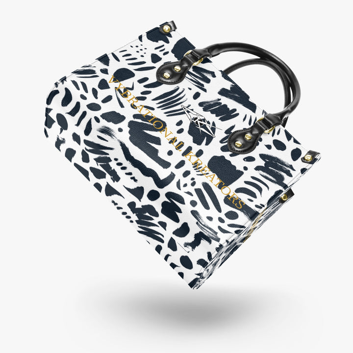 Kreator Luxe tote bag by Vybrational Kreators featuring a black and white abstract pattern structured shape black top handles gold hardware and printed brand logo.
