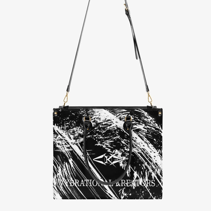 Onyx Flow Luxe tote bag by Vybrational Kreators featuring a black and white abstract flow pattern structured silhouette black top handles gold hardware and printed brand logo.
